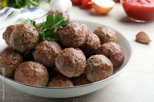 Tasty cooked meatballs with parsley on white wooden table, closeup