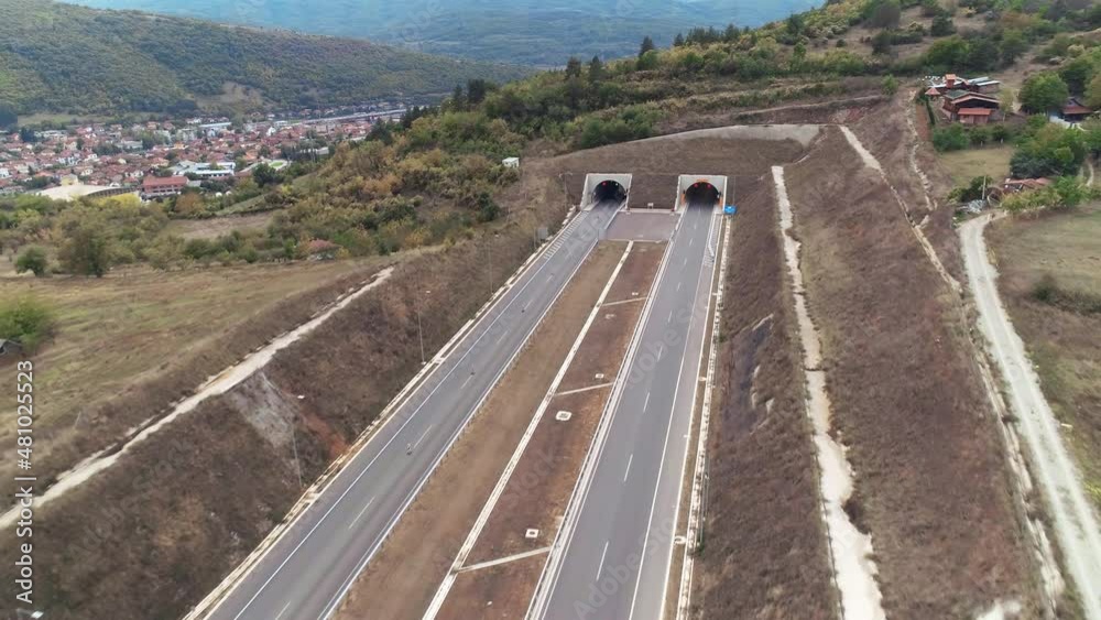 Highway entering a tunnel, town behind. Road exiting the tunnel. Aerial drone shot, Serbia. Highway entering a tunnel, town behind. Road exiting the tunnel. Aerial drone shot, Serbia.