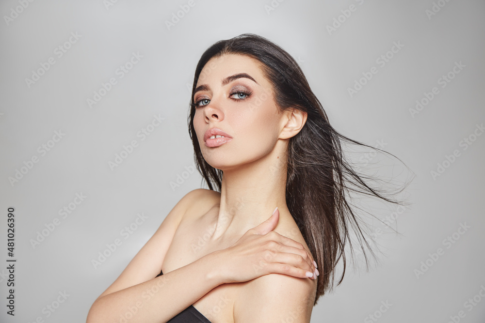 Naklejka premium beautiful makeup on a young girl. studio portrait of a woman with clear skin on a gray background. natural beauty