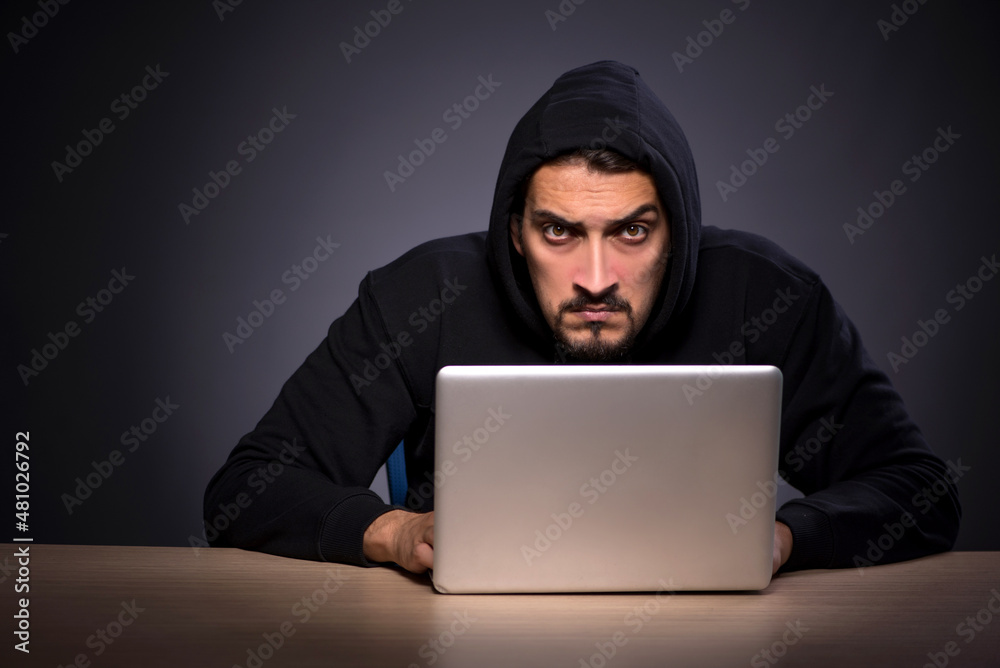 Young male hacker on grey background Young male hacker on grey background