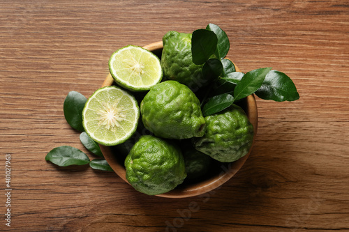 Fresh ripe bergamot fruits with green leaves on wooden table, top view