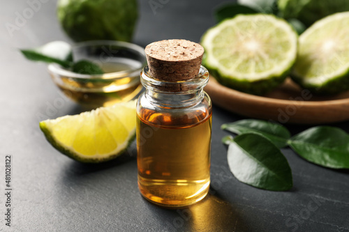 Bottle of bergamot essential oil on dark table, closeup