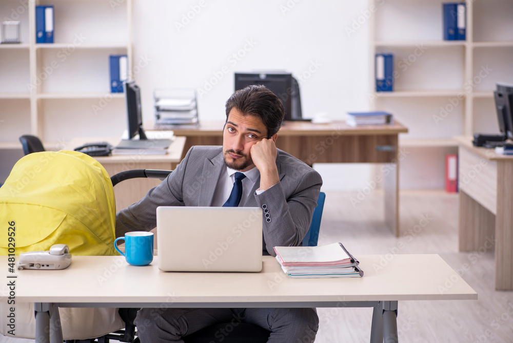 Young male employee looking after new born at workplace Young male employee looking after new born at workplace