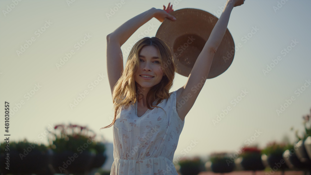 Attractive girl taking off sunhat in sunny day. Young lady enjoying springtime.