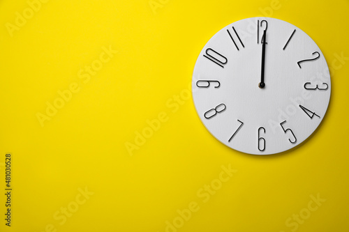 Modern clock on yellow background, top view. Space for text