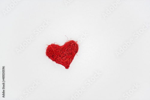 On white snow  a rattan red heart against the backgroundof a snowy forest. Holiday card with love