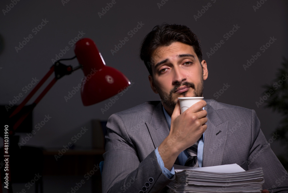 Naklejka premium Young male employee working late in the office