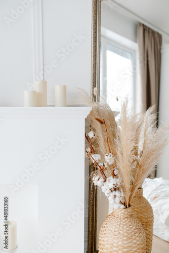 White interior in minimalism style. Dried flowers pampas grass and cotton in a vase. Beautiful and stylish interior.