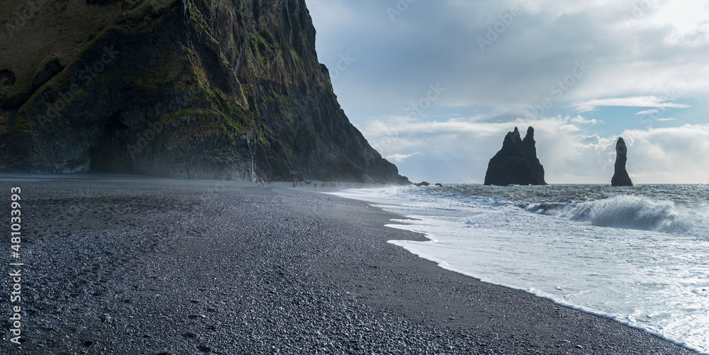 The famous Black Sand ocean Beach, mount Reynisfjall and Picturesque Basalt Columns, Vik, South Iceland. People unrecognizable.