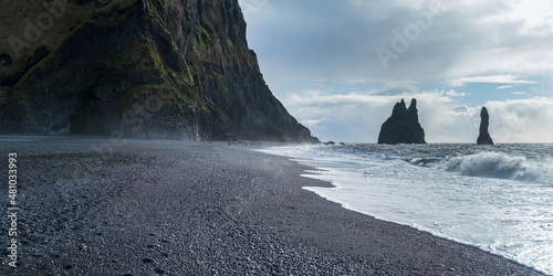 The famous Black Sand ocean Beach, mount Reynisfjall and Picturesque Basalt Columns, Vik, South Iceland. People unrecognizable.