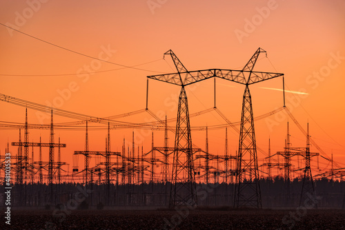 Silhouettes of electric power lines at sunset