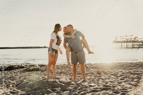 happy family. Dad rides daughter on back on the seashore.  © andrey