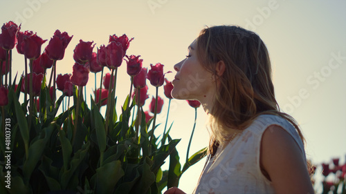 Closeup woman face profile smelling flowers in sun reflecction bright sunny day. photo