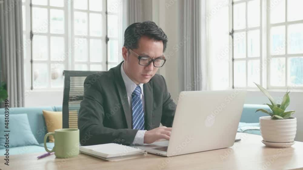 Asian Businessman With Glasses Wearing Business Suit Typing On Computer While Working At Home.
Asian Businessman With Glasses Wearing Business Suit Typing On Computer While Working At Home.