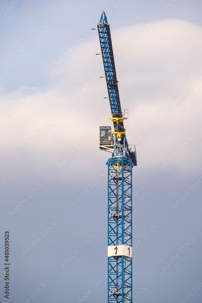 A modern construction crane against cloudy sky on a sunny winter day. A modern construction crane against cloudy sky on a sunny winter day.