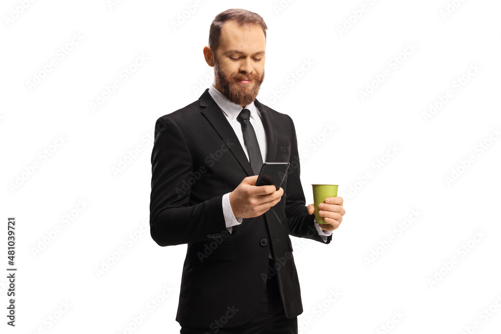 Young businessman holding a paper coffee cup and typing on a mobile phone Young businessman holding a paper coffee cup and typing on a mobile phone