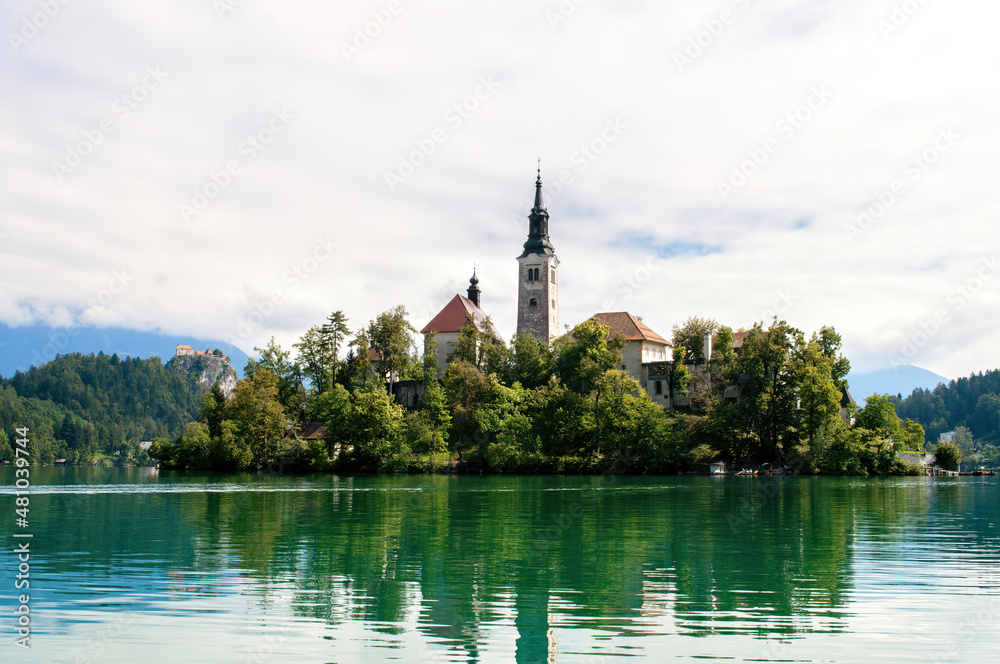 Church on an island in the middle of Lake Bled in Slovenia. Church tower illuminated by the sun with reflection in the lake.