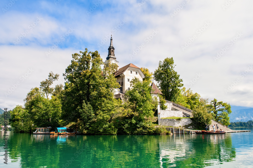 Church on an island in the middle of Lake Bled in Slovenia. Church tower illuminated by the sun with reflection in the lake.