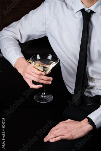 A man drinking martini cocktail with olives