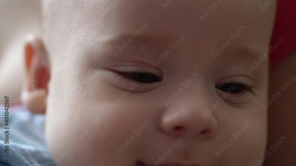 Close-up Smiling Face Of Newborn Baby In Early Days Wakes Up Opens Eyes. Infant Child Grimaces After Dream In Blue Bodysuit. Kid In First Minutes Of Life Portrait In Macro. Childhood, Infancy Concept Close-up Smiling Face Of Newborn Baby In Early Days Wakes Up Opens Eyes. Infant Child Grimaces After Dream In Blue Bodysuit. Kid In First Minutes Of Life Portrait In Macro. Childhood, Infancy Concept