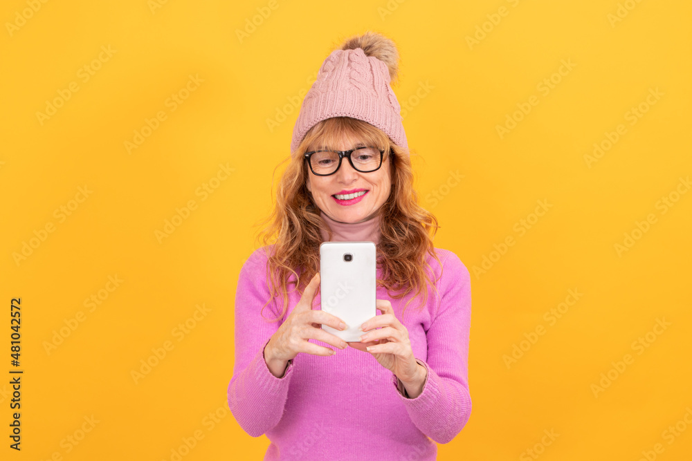 Φωτογραφία woman isolated on background wearing winter clothes looking at mobile phone, spa