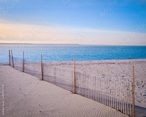 Beach seascape with sand fence, footprints, and wind traces at sunrise on Cape Cod photo