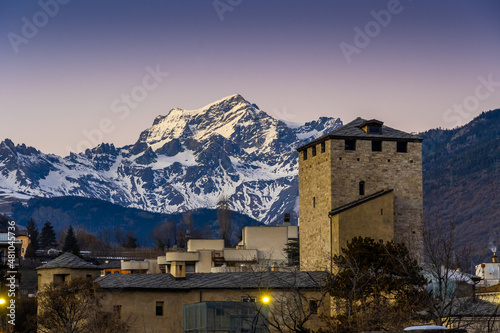 Aosta, sunset on the medieval tower with the snow-capped mountains on the background 