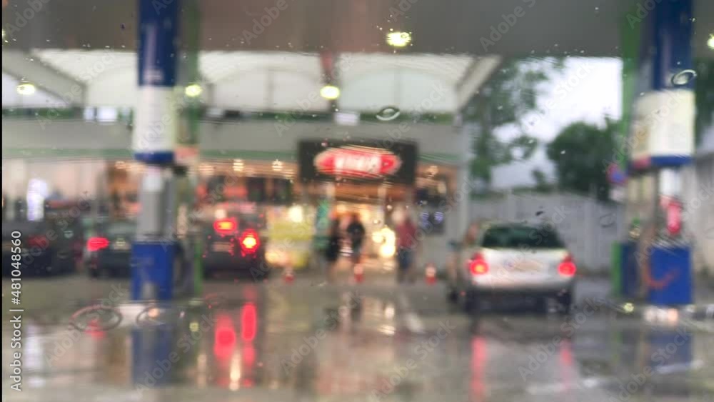 Blurred background of the gas station, Raindrops on the car window. Wiper moves. Blurred background of the gas station, Raindrops on the car window. Wiper moves.