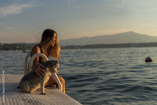 Cute Latin girl with her pet dog schnauzer at the lake on an afternoon photo