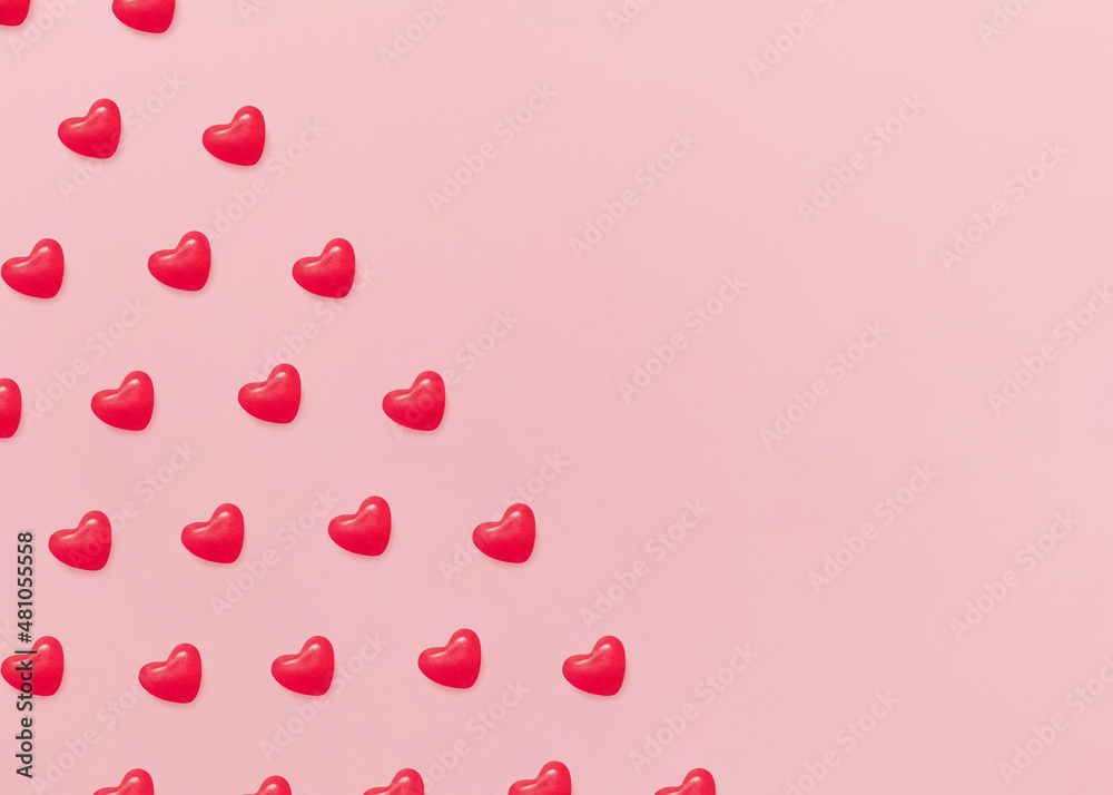 Valentine's day. Design template with copy space. Many red sugar candies in heart shapes on pink backdrop