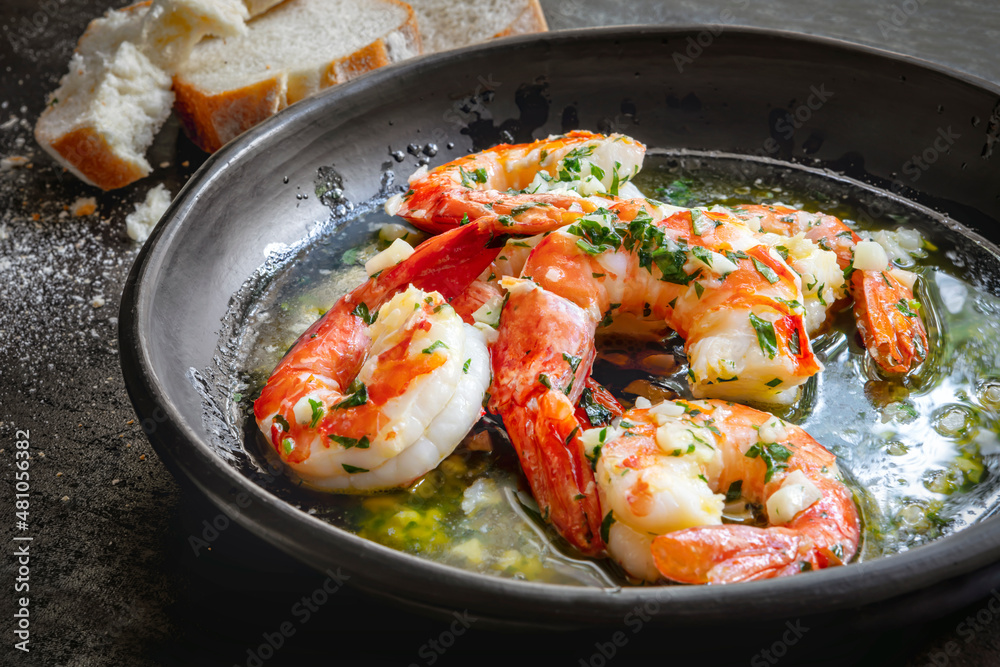 Garlic Prawns or Shrimp in black rustic bowl with crusty bread Garlic Prawns or Shrimp in black rustic bowl with crusty bread