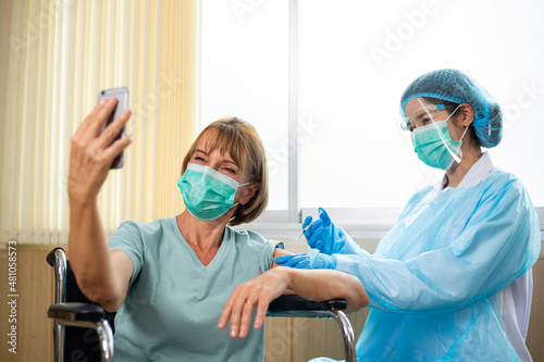 Senior adult using smart phone for selfie yourself after received vaccine photo