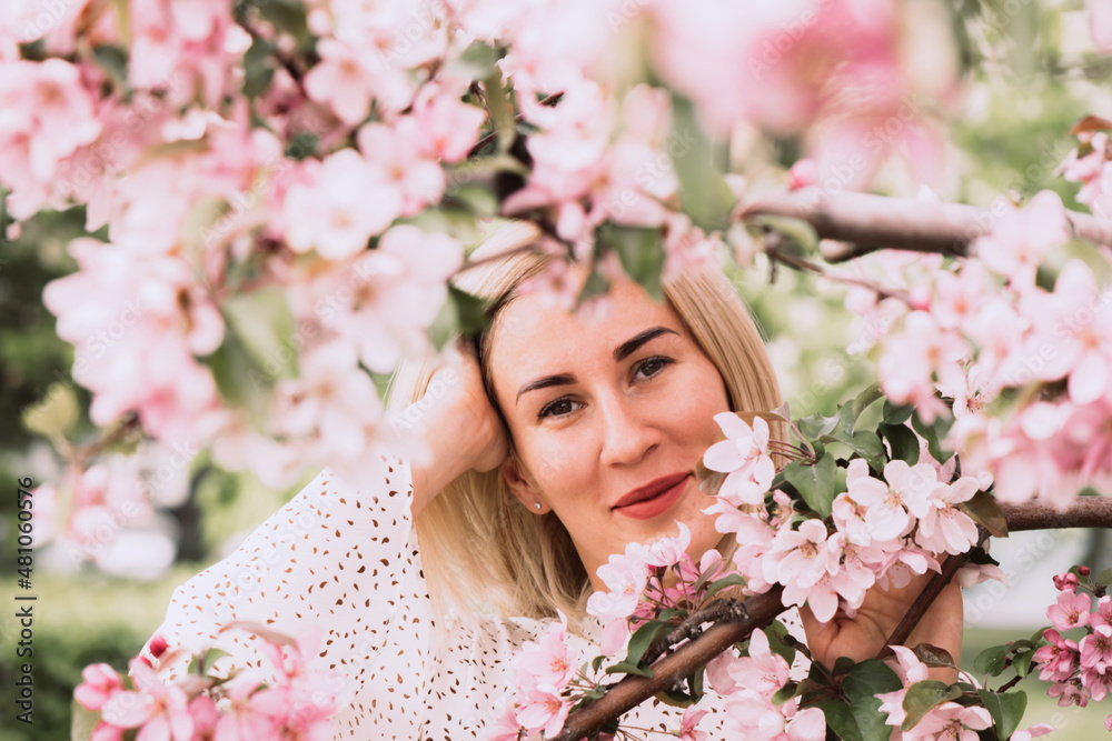 Young woman among the blossoming trees. Spring nature park or garden, flowering trees. Concept spring woman health Young woman among the blossoming trees. Spring nature park or garden, flowering trees. Concept spring woman health