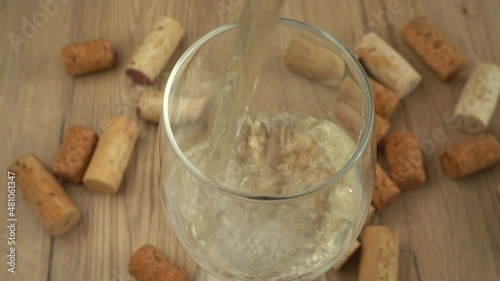 Wine is poured into a glass on the background of wine corks. photo