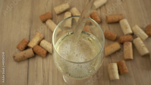 Wine is poured into a glass on the background of wine corks. photo