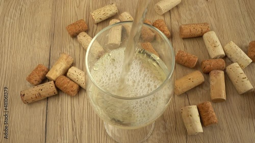 Wine is poured into a glass on the background of wine corks. photo