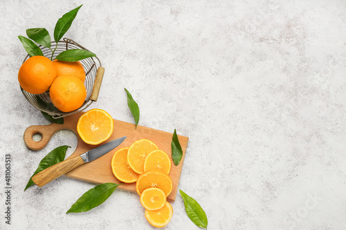 Basket with fresh juicy oranges on light background