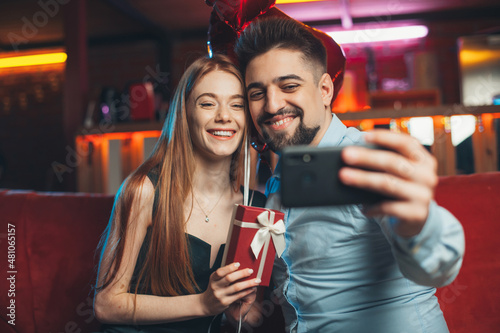 Caucasian couple taking selfie celebrating Valentine's day. Festive gift surprise.