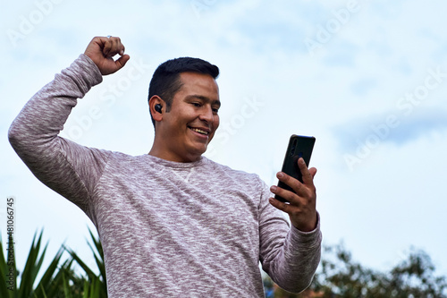 la felicidad de un joven al recibir buenas noticias en su teléfono móvil  photo