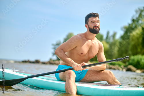 Well-built young man in blue shorts kayaking