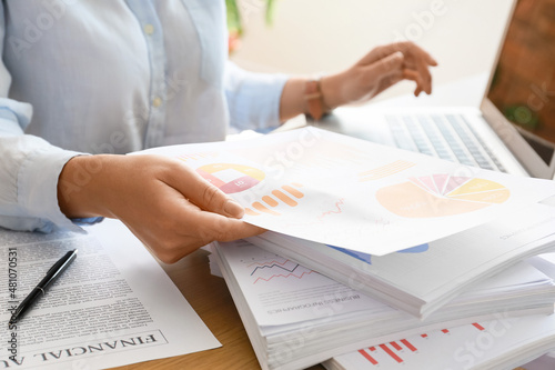 Businesswoman working with stack of documents at desk in office, closeup