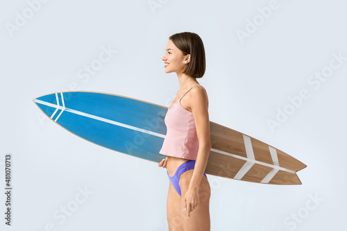 Beautiful young woman with surfboard on light background © Pixel-Shot