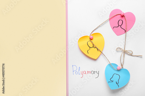 Clipboard with paper hearts and word POLYAMORY on color background