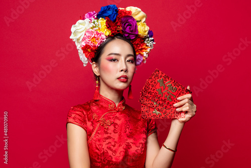 Elegant Asian woman in traditional oriental costume holding red envelopes or Ang Pow in isolated background for Chinese new year concepts, foreign text translates as great luck great profit