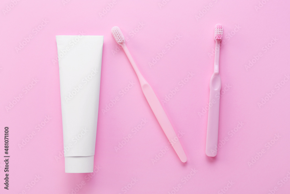 Tube with tooth paste and brushes on pink background
