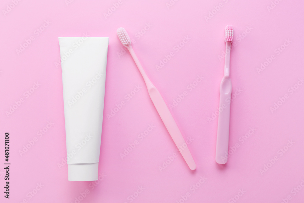 Tube with tooth paste and brushes on pink background Tube with tooth paste and brushes on pink background