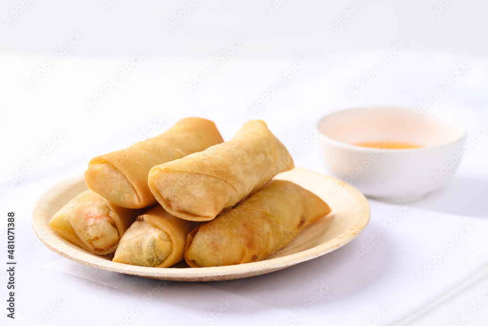 Asian deep fried spring roll filling with tofu, cabbage, carrot and glass noodle on natural plate eating with dipping sauce. Vegan food Asian deep fried spring roll filling with tofu, cabbage, carrot and glass noodle on natural plate eating with dipping sauce. Vegan food