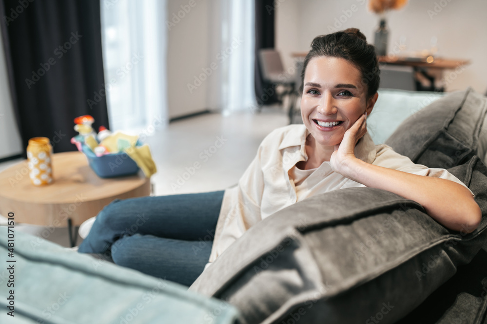 Smiling young woman sitting at home on the sofa