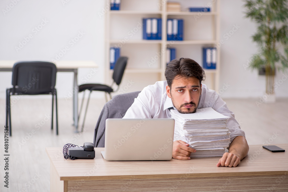 Young male employee and too much work in the office Young male employee and too much work in the office