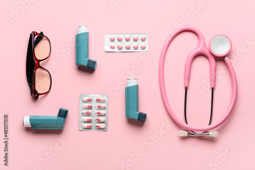 Eyeglasses, stethoscope, pills and asthma inhalers on color background